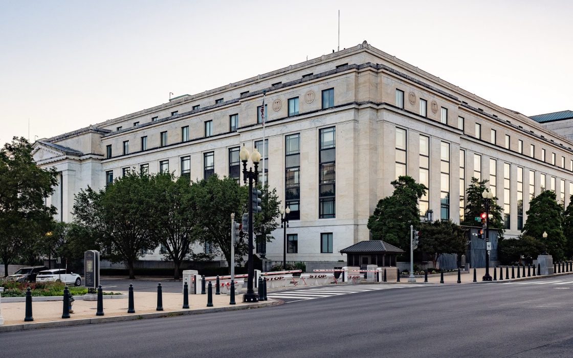 Limestone facade of the Dirksen Senate Office Building at dusk with trees and street lamps along the sidewalk