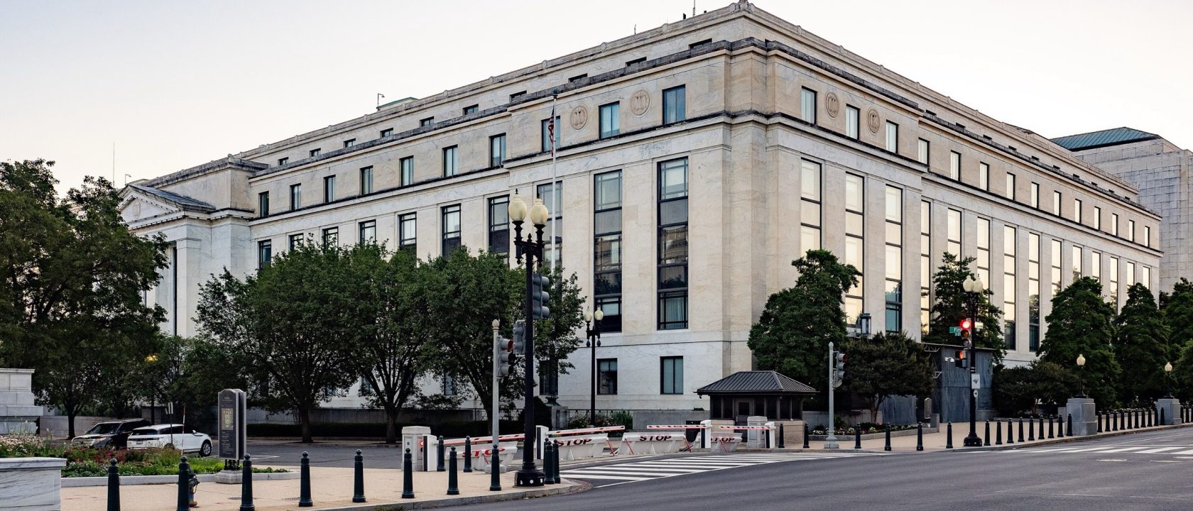 Limestone facade of the Dirksen Senate Office Building at dusk with trees and street lamps along the sidewalk
