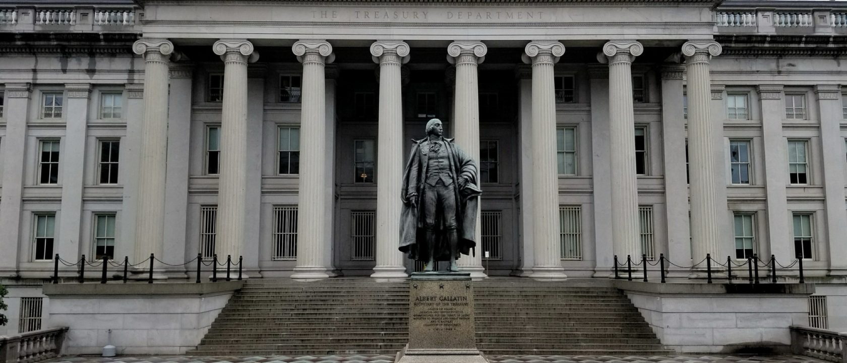Bronze statue of Albert Gallatin in front of the columned facade of the US Treasury Building