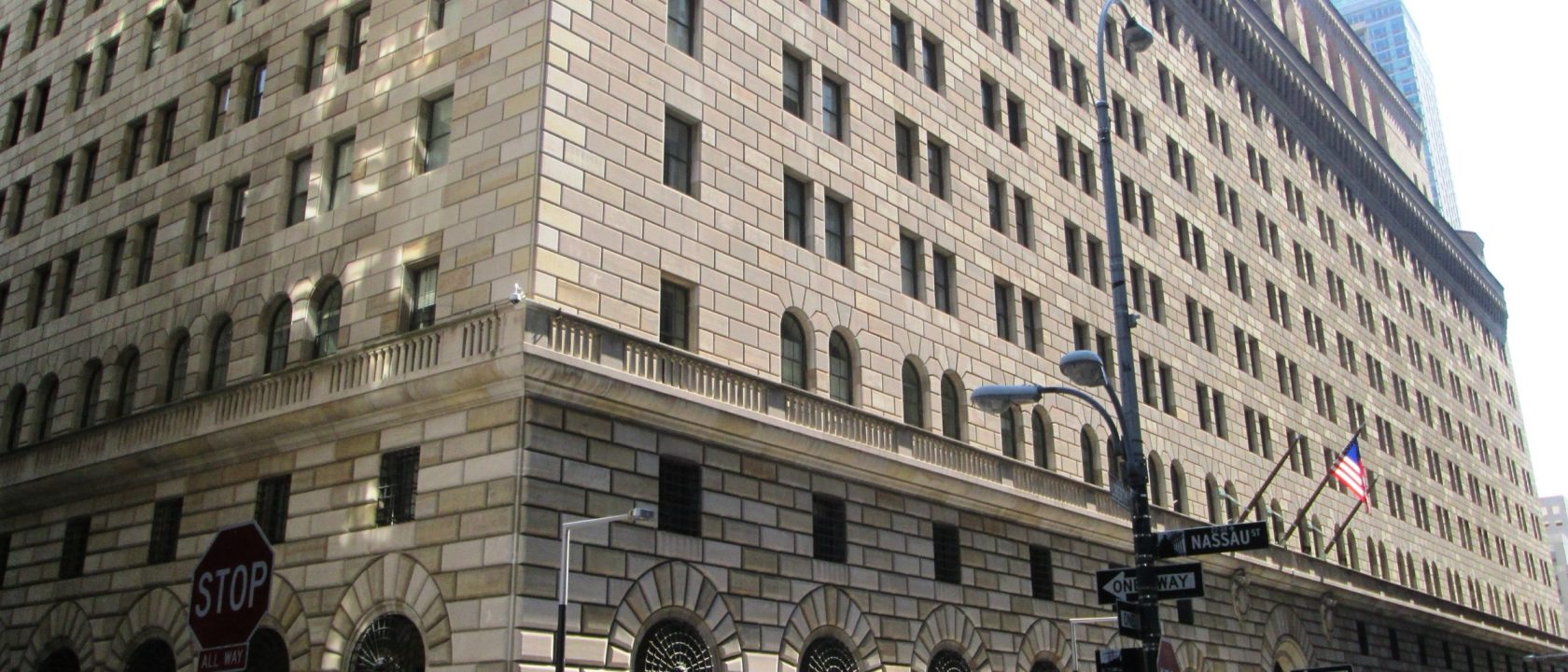 Stone facade of the Federal Reserve Bank of New York building on a Lower Manhattan street corner