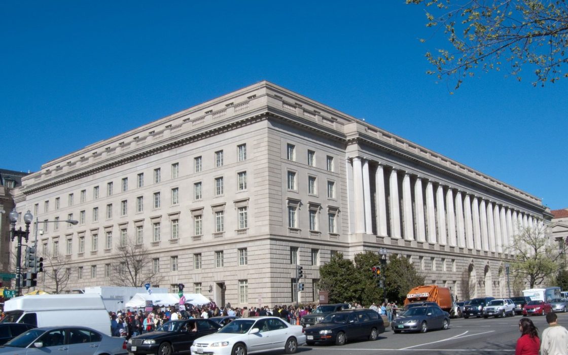 Large neoclassical IRS headquarters building with columns on Constitution Avenue, cars in the foreground.
