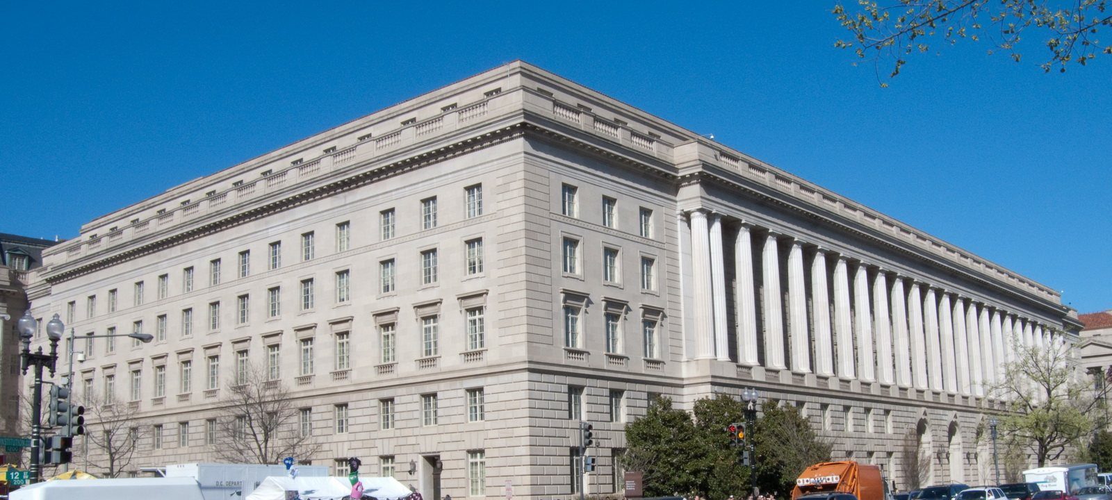 Large neoclassical IRS headquarters building with columns on Constitution Avenue, cars in the foreground.
