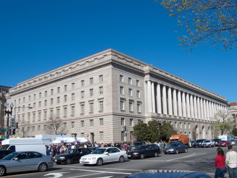 Large neoclassical IRS headquarters building with columns on Constitution Avenue, cars in the foreground.