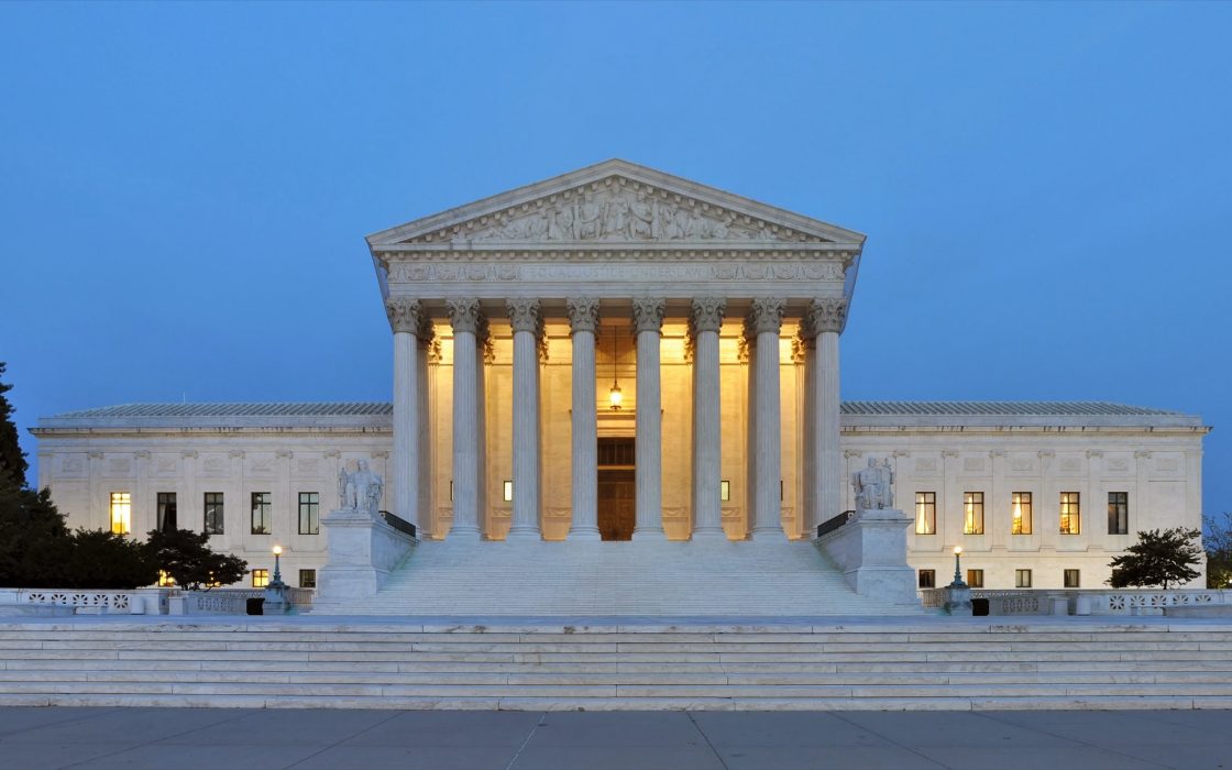 Panoramic view of the U.S. Supreme Court Building's marble columns lit at dusk