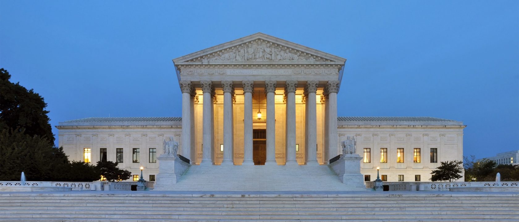 Panoramic view of the U.S. Supreme Court Building's marble columns lit at dusk