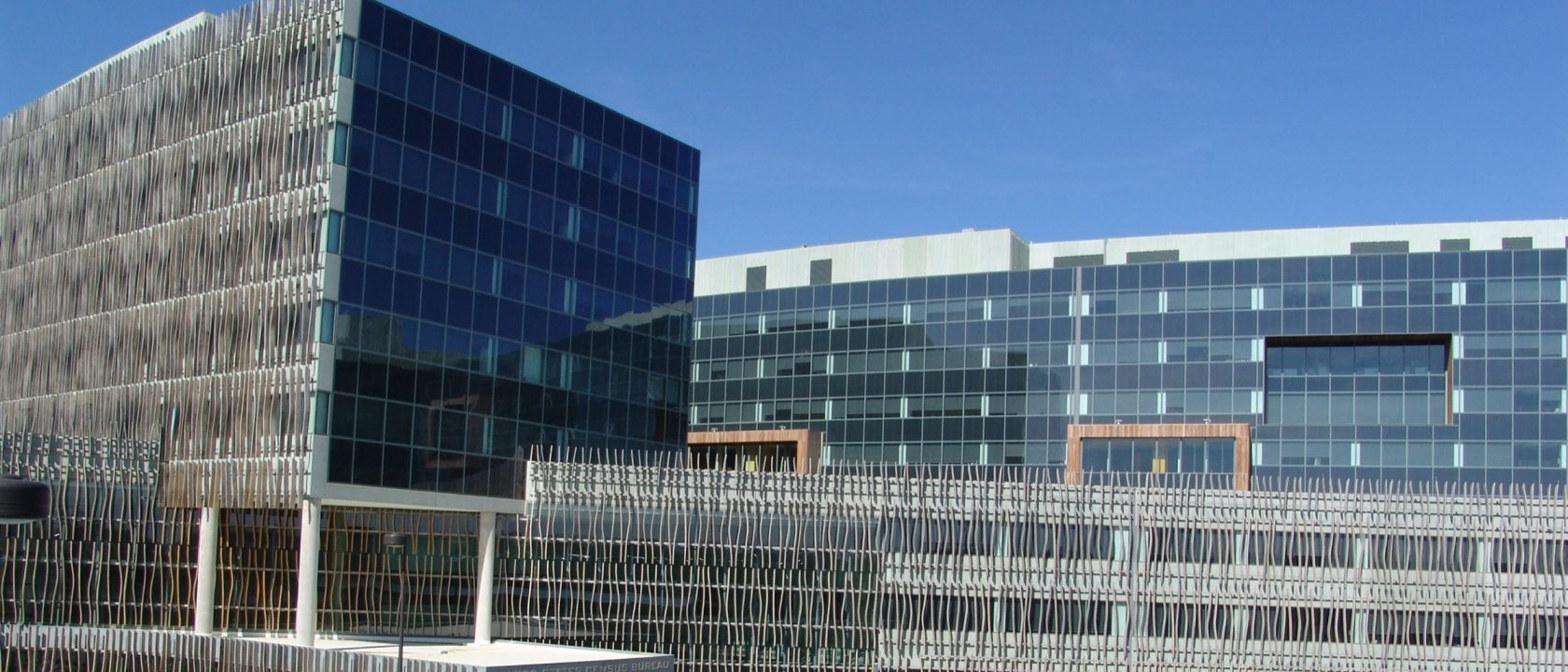 Glass and wood-slatted federal office buildings under a clear blue sky