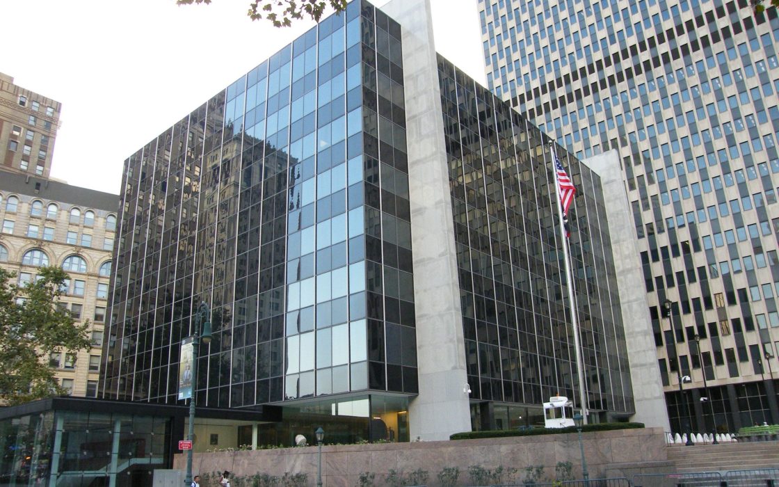 Glass-fronted Court of International Trade building in Manhattan with a US flag outside
