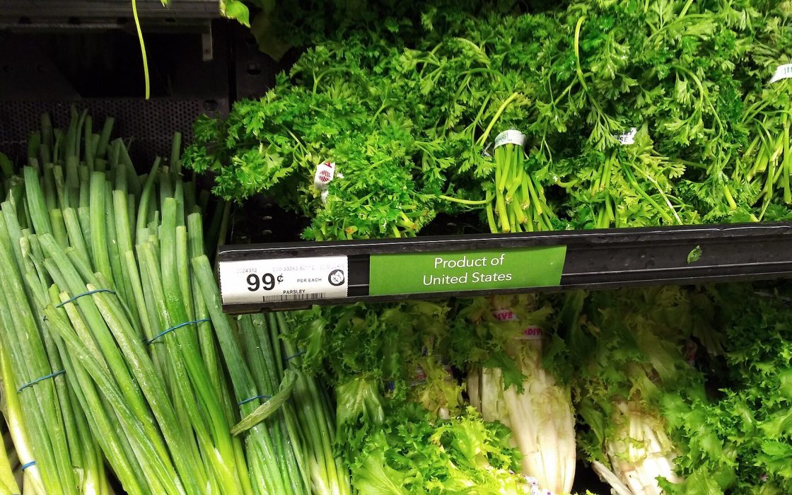 Bunches of parsley and green onions on a supermarket shelf with a 99-cent price tag