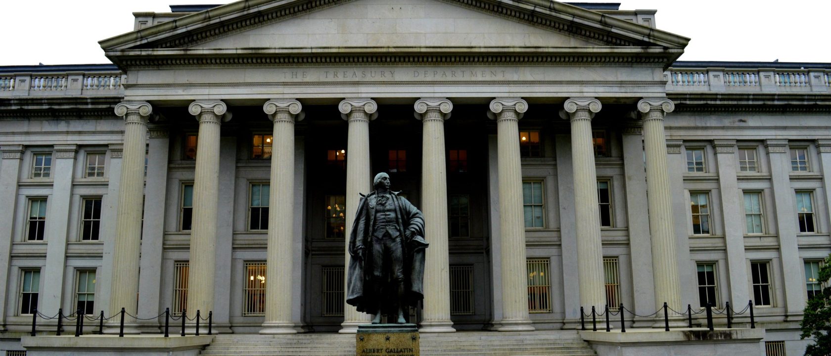 Columned facade of the U.S. Treasury Department building with a statue in front