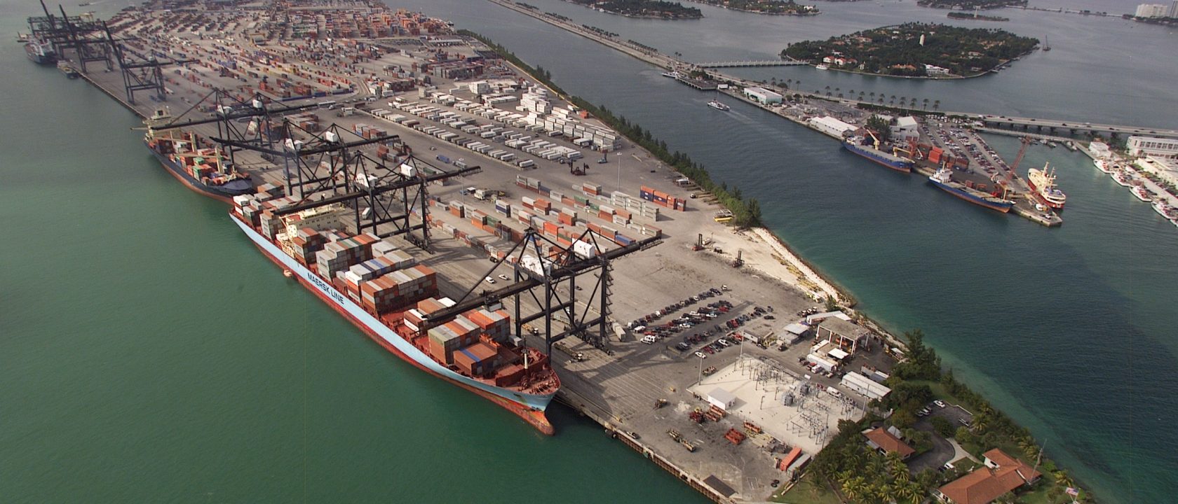 Aerial view of a container port with cranes loading stacked containers onto ships